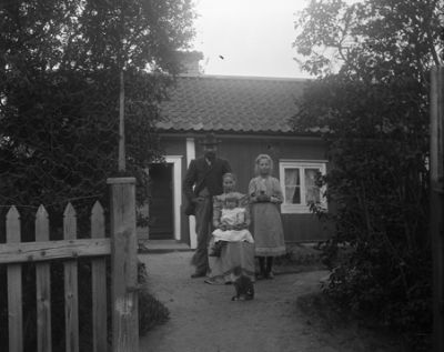 Man, kvinna och 2 barn framför hus
Nyckelord: Hus 
