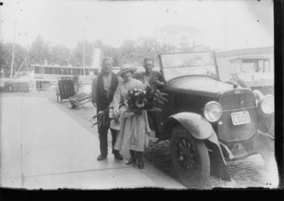 2 män och 1 kvinna stående vid en bil.
Nyckelord: Dräkt Bil