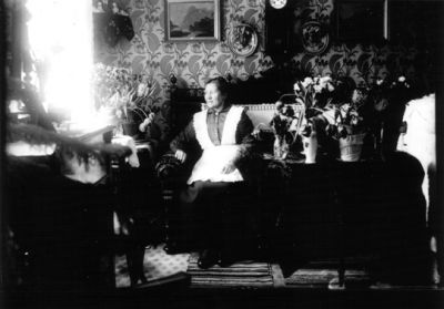 Kvinna sittande i soffa.
Nyckelord: Finrum Blommor