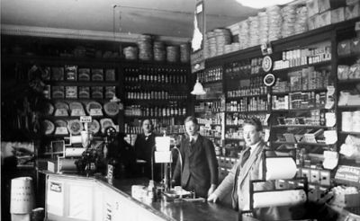 3 män stående bakom disken i affär.
Nyckelord: Affärsinredning