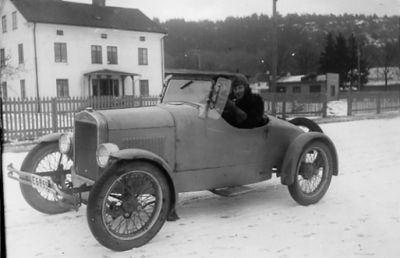 Man sittande i bil framför byggnad.
Nyckelord: Bil