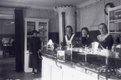 3 kvinnor stående bakom disken i konditori.
Nyckelord: Kakor