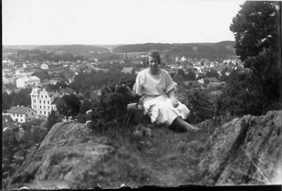 Kvinna sittande på berg med bebyggelse i bakgrunden.
Nyckelord: Utsikt