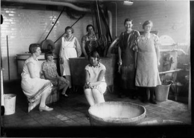 3 kvinnor sittande och 4 stående i tvätteri.
Nyckelord: Tvättkar