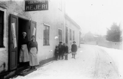 2 kvinnor och 5 barn stående utanför byggnad.
Nyckelord: Vinter