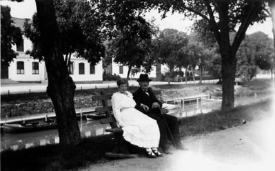 Man och kvinna sittande på bänk vid vattendrag.
Nyckelord: Storån