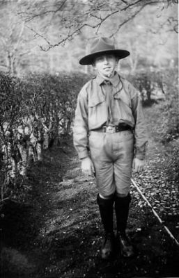 Scoutpojke stående i trädgård.
