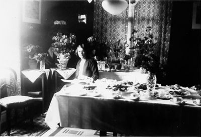 Kvinna sittande vid kaffebord.
Nyckelord: Blommor