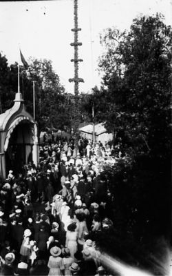 Ett antal personer stående framför estrad.
Nyckelord: Midsommarfirande