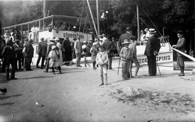 Ett antal personer gående och stående vid båt.
