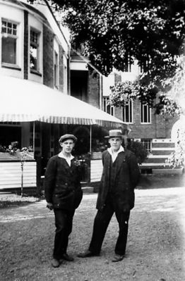 2 män stående framför byggnad.
