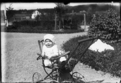 Barn sittande i barnkärra.
Nyckelord: Barnvagn