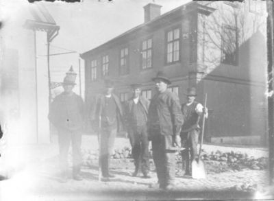 5 män stående i gatukorsning.
Nyckelord: Kullersten Skyffel Verktyg Dräkt Klockkedja