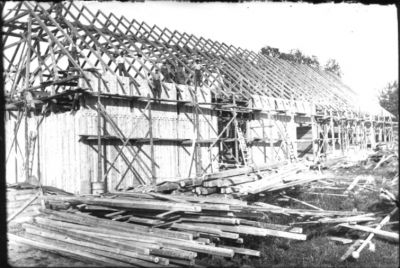 Ett antal män stående vid ett husbygge.
Nyckelord: Byggnadsställning