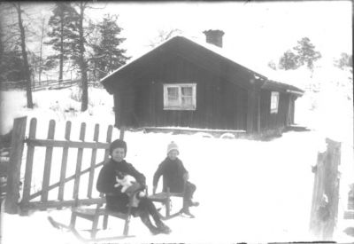 2 barn med katt sittande på kjälkar.
Nyckelord: Katt Kjälke Vinter