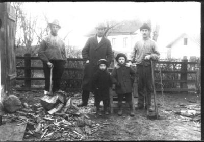 3 män och 2 barn stående på vedbacken.
Nyckelord: Yxa Såg