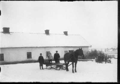 2 män och ett barn stående vid hästekipage.
Nyckelord: Häst Släde Vinter