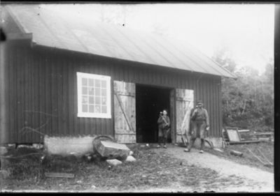 Man och pojke stående i dörröppning på uthus.
Nyckelord: Slägga Smedhammare Smedtång