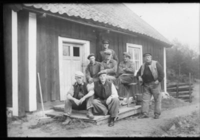 7 män stående och sittande på trappa.
Nyckelord: Trappa Bänk