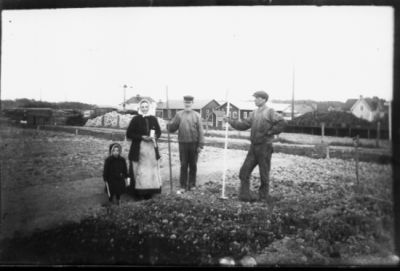 2 män, kvinna och ett barn stående på plan.
