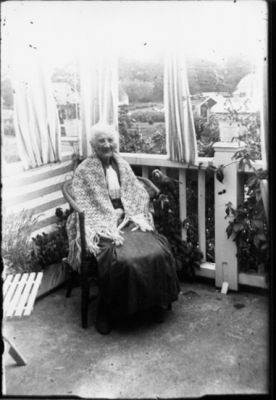 Kvinna sittande i stol på balkong.
