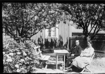 Man och kvinna sittande i trädgård.
Nyckelord: Trädgård Trädgårdsmöbel