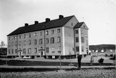 Man stående framför byggnad.
Nyckelord: Byggnad