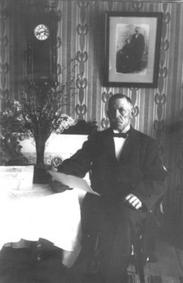 Man sittande vid bord.
Nyckelord: Tavla Klocka