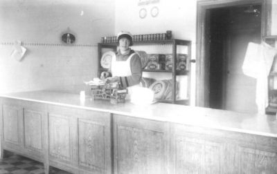 Kvinna stående bakom disken i affär.
Nyckelord: Butik Våg