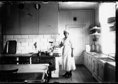 Kvinna stående vid spisel i ett kök.
Nyckelord: Spisel Diskbänk