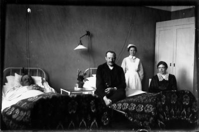 Man sittande, kvinna sittande, kvinna stående och man liggande i säng.
Nyckelord: Säng Uniform