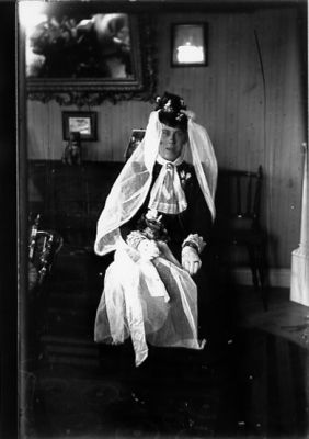 Utklädd man sittande på stol.
Nyckelord: Maskerad