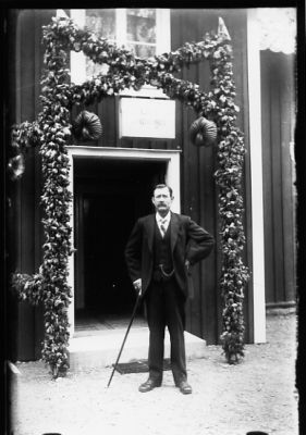 Man stående under portal.
Nyckelord: Högtid Portal Käpp