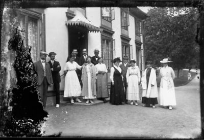 Ett antal personer stående framför byggnad.
Nyckelord: Gårdsplan Dräkt