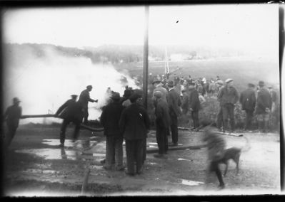 Ett antal personer stående vid brand.
Nyckelord: Brandrök