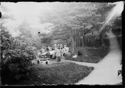 Ett antal personer sittande vid bord i naturen.
