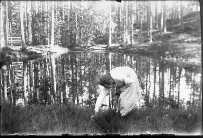 Kvinna stående vid tjärn.
Nyckelord: Tjärn Skog