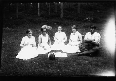 Man och 4 kvinnor sittande i gräset drickandes kaffe.
Nyckelord: Skogsbacke Picnic