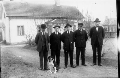 5 män och hund stående framför byggnad.
Nyckelord: Hund Grusgång