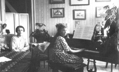 Kvinna sittande vid piano och kvinna sittande bredvid.
Nyckelord: Piano Tavla Klocka