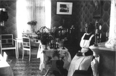 Kvinna sittande i rum.
Nyckelord: Blommor Tavla Tapet