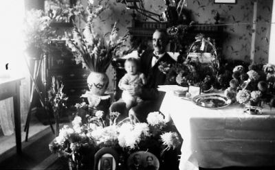 Man sittande med barn i knät i rum med blommor och presenter.
Nyckelord: Födelsedag Blommor Presenter