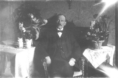 Man sittande i rum med blommor.
Nyckelord: Blommor