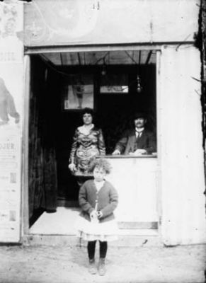 Man sittande, kvinna och flicka stående i dörröppning.
Nyckelord: Dörröppning Byggnad