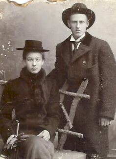 Sittande kvinna och stående man
Nyckelord: Dräkt Hatt