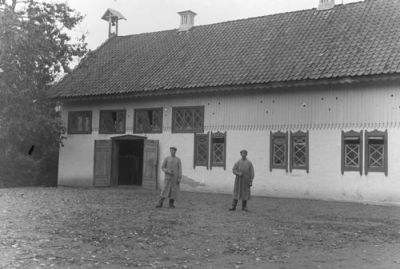 2 män i långa rockar framför ladugårdsbyggnad
Nyckelord: Snickarglädje Klocka