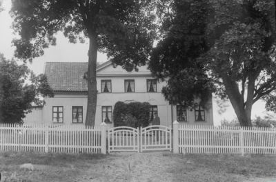 En man stående på gårdsplan framför vitputsad byggnad
