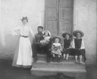 Man kvinna och 4 flickor vid trappa till hus
Nyckelord: Dräkt