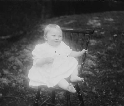 Liten flicka sittande på pinnstol i naturen
