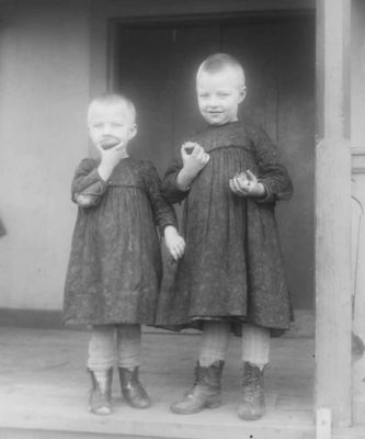 2 barn stående på veranda
Nyckelord: Dräkt